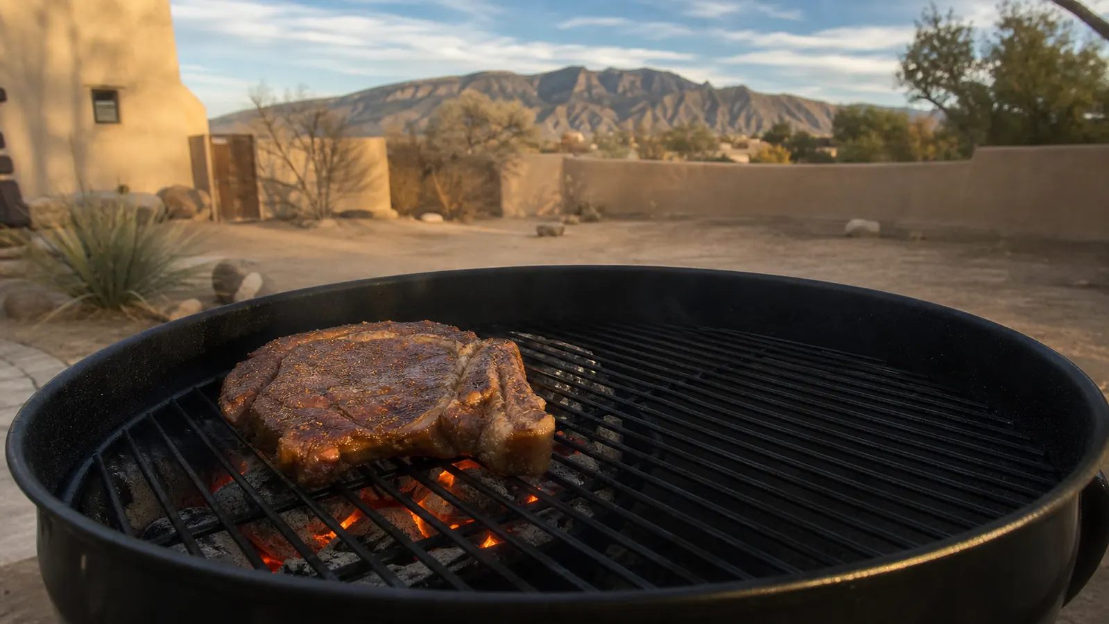 A thick ribeye steak searing directly over a mound of glowing coals in an open black kettle grill